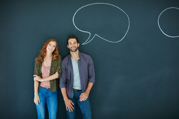 She likes a man who speaks his mind. Portrait of a young couple standing in front of a blackboard with speech bubbles drawn on it.