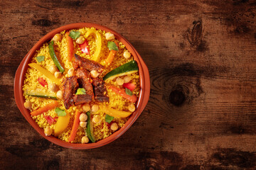 Meat and vegetable couscous in a bowl, typical food from Morocco, a traditional festive Arabic dish with herbs and spices, shot from the top - obrazy, fototapety, plakaty