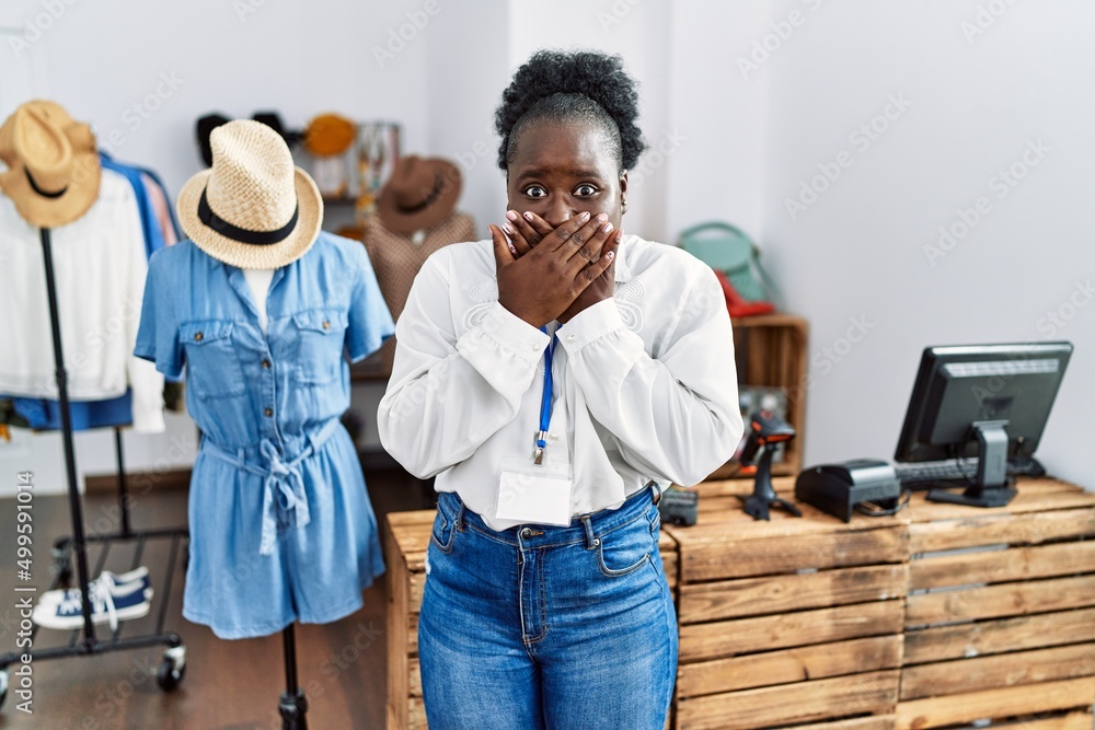 Poster Young african woman working as manager at retail boutique shocked covering mouth with hands for mistake. secret concept.