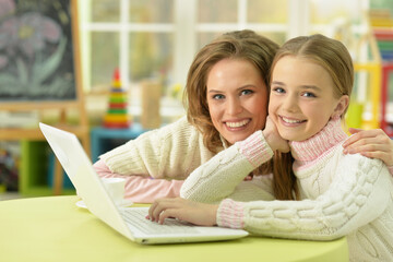 Portrait of mother and daughter using laptop