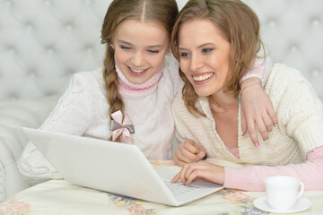 Portrait of mother and daughter using laptop together