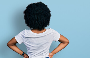 Young african american woman wearing casual white t shirt standing backwards looking away with arms on body