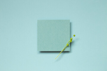 Blue blank memo paper with dry flower on blue background. top view, copy space