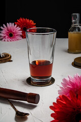 A boston glass filled with ingredients in preparation for making a French Martini cocktail, on a white background and styled with flowers and bar equipment.