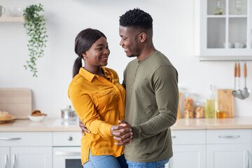 Romantic Black Man And Woman Dancing Together At Home In Kitchen Interior