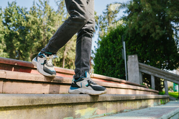 Close-up legs walking down the stairs in a city park. The young man goes down the stairs to meet his friends.