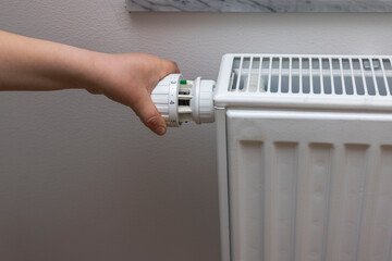Close up view of child's hand turning off thermostat on heating radiator to save energy. Sweden.