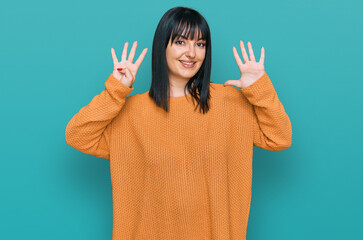 Young hispanic woman wearing casual clothes showing and pointing up with fingers number nine while...