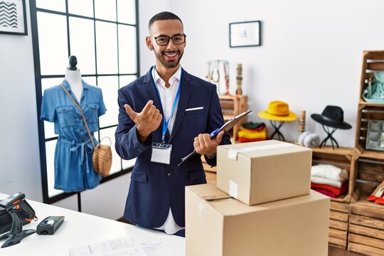 African american man working as manager at retail boutique beckoning come here gesture with hand inviting welcoming happy and smiling