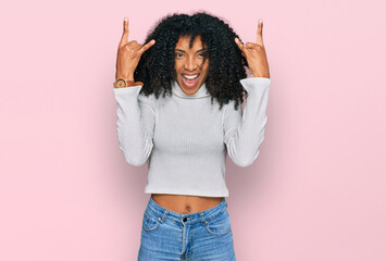 Young african american girl wearing casual clothes shouting with crazy expression doing rock symbol...