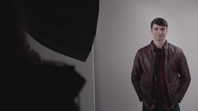 Good-Looking Man Wearing Leather Jacket Modelling In Photo Studio On White Background. Slow Motion