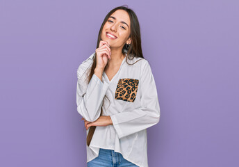 Young hispanic girl wearing casual clothes looking confident at the camera with smile with crossed arms and hand raised on chin. thinking positive.