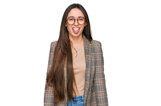 Young hispanic girl wearing business clothes and glasses sticking tongue out happy with funny expression. emotion concept.