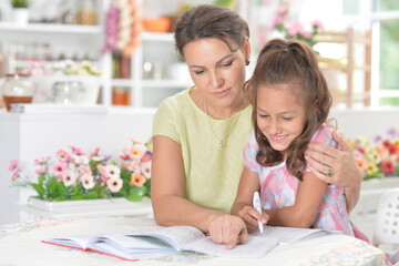 Obraz premium Cute little girl with her mother doing homework together