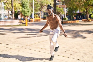 African american woman shirtless jumping at park