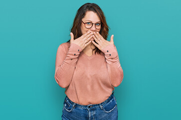 Young plus size woman wearing casual clothes and glasses laughing and embarrassed giggle covering...