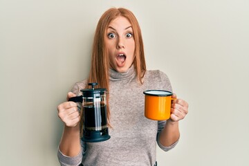 Young irish woman drinking italian coffee afraid and shocked with surprise and amazed expression, fear and excited face.