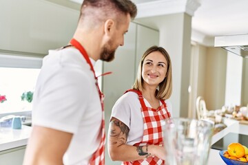 Young couple smiling confident making smoothie cooking at kitchen