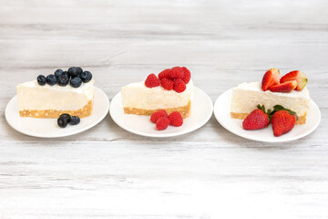 Classic sliced cheesecake with fresh berries - strawberry, raspberries and  blueberries, close up. No baked, Tasty cake with cheese  