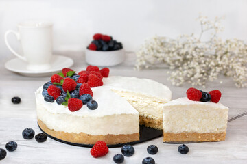Classic sliced cheesecake with fresh berries - raspberries and  blueberries, close up. No baked, Tasty cake with cheese  