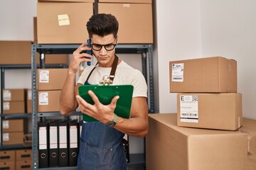 Young hispanic man ecommerce business worker talking on the smartphone at office