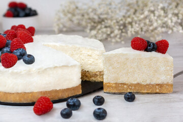 Classic sliced cheesecake with fresh berries - raspberries and  blueberries, close up. No baked, Tasty cake with cheese  