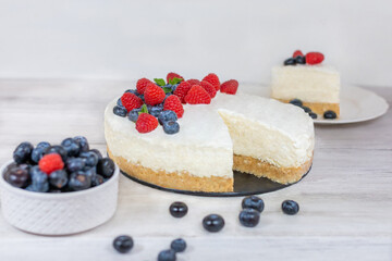 Classic sliced cheesecake with fresh berries - raspberries and  blueberries, close up. No baked, Tasty cake with cheese  