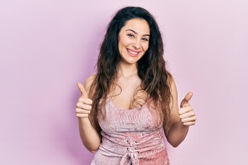 Young hispanic woman wearing casual clothes success sign doing positive gesture with hand, thumbs up smiling and happy. cheerful expression and winner gesture.