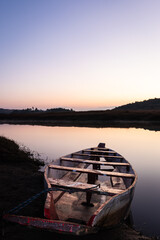 traditional wood boat at calm lake with dramatic sunrise colorful sky reflection at morning
