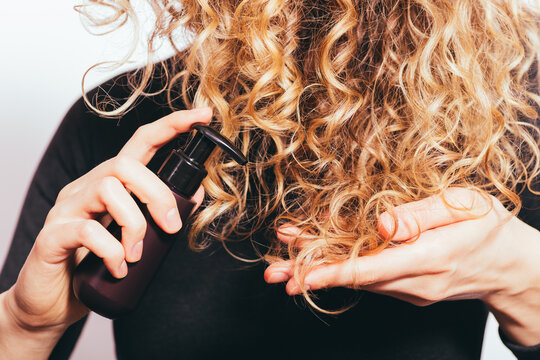 Young woman applying oil to her curly hair