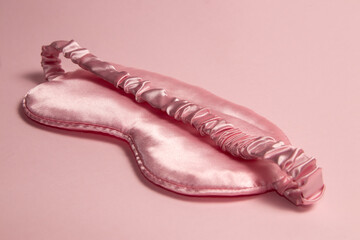 Pink silk sleeping mask on a pastel pink background