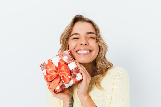 Satisfied happy blonde young woman holding gift box