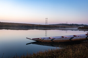 traditional wood boat at calm lake with dramatic sunrise colorful sky reflection at morning
