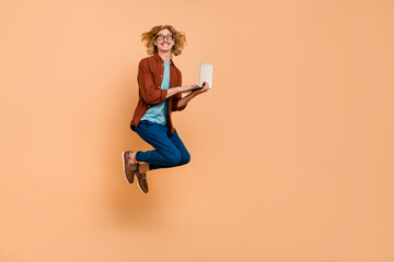 Fototapeta na wymiar Full length body size view of handsome trendy cheerful guy jumping writing email isolated over beige pastel color background