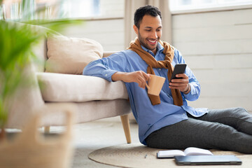 Portrait of smiling young man using smartphone at home