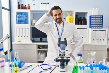 Young hispanic man with beard working at scientist laboratory confuse and wonder about question....