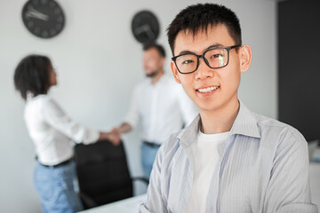 Cheerful Asian manager near colleagues