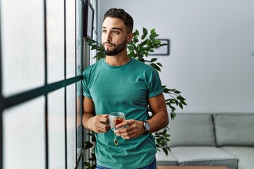 Young arab man smiling confident drinking tea at home