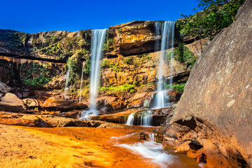 waterfall falling from mountain top with blue sky at morning from unique angle