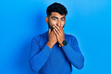 Fototapeta na wymiar Arab man with beard wearing casual blue sweater shocked covering mouth with hands for mistake. secret concept.