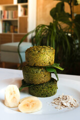 SPINACH GLUTEN-FREE MUFFINS: close-up of three spinach muffins with banana slices and oat flakes on white plate.