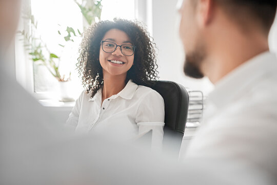 Smiling ethnic female talking with male coworkers in office