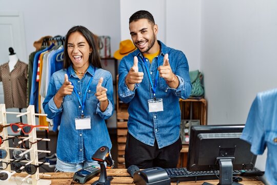 Young interracial people working at retail boutique pointing fingers to camera with happy and funny face. good energy and vibes.