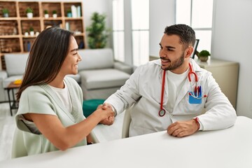 Doctor shaking hand with latin woman patient at clinic.