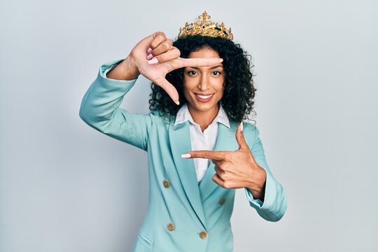 Young latin girl wearing business clothes and queen crown smiling making frame with hands and fingers with happy face. creativity and photography concept.