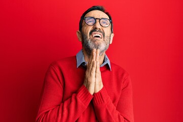 Middle age hispanic man wearing casual clothes and glasses begging and praying with hands together with hope expression on face very emotional and worried. begging.