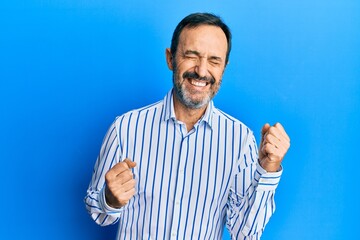 Fototapeta premium Middle age hispanic man wearing casual clothes excited for success with arms raised and eyes closed celebrating victory smiling. winner concept.