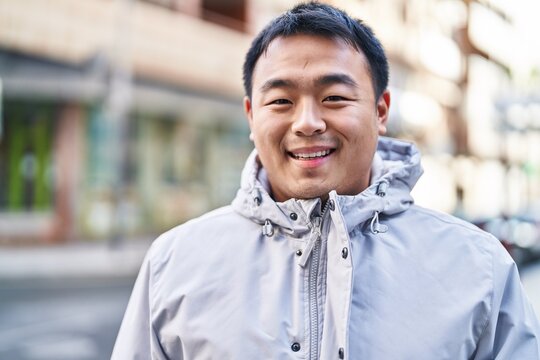 Young chinese man smiling confident standing at street