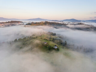 Mountain settlement in the Ukrainian Carpathians in the morning mist. Aerial drone view.