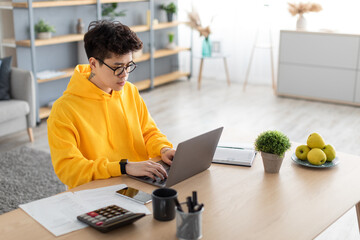 Focused asian man working on laptop at home
